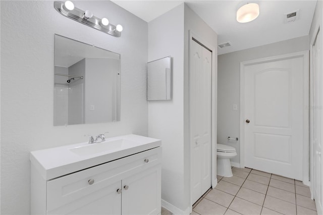 bathroom featuring vanity, a shower, tile patterned floors, and toilet