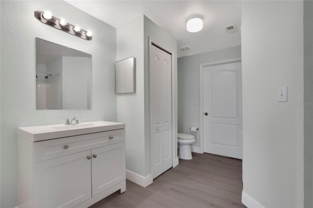 bathroom with vanity, wood-type flooring, a shower, and toilet