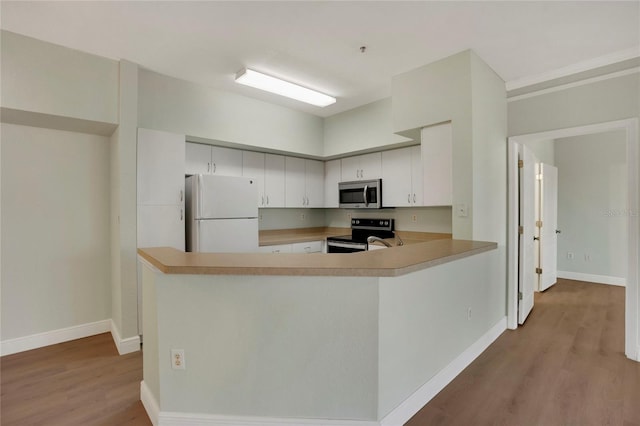 kitchen with white cabinetry, electric range oven, white fridge, kitchen peninsula, and light wood-type flooring