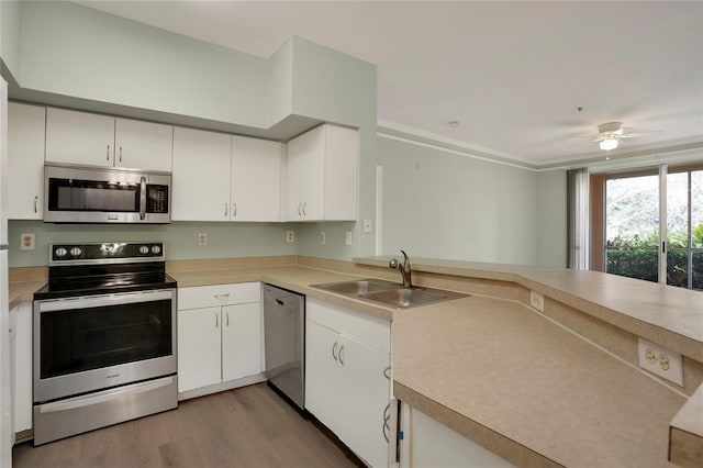 kitchen featuring sink, light hardwood / wood-style flooring, appliances with stainless steel finishes, kitchen peninsula, and white cabinets