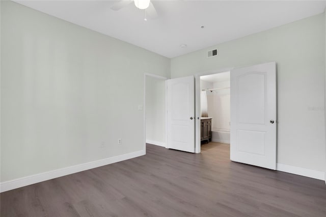 unfurnished bedroom featuring dark wood-type flooring, ceiling fan, and ensuite bathroom