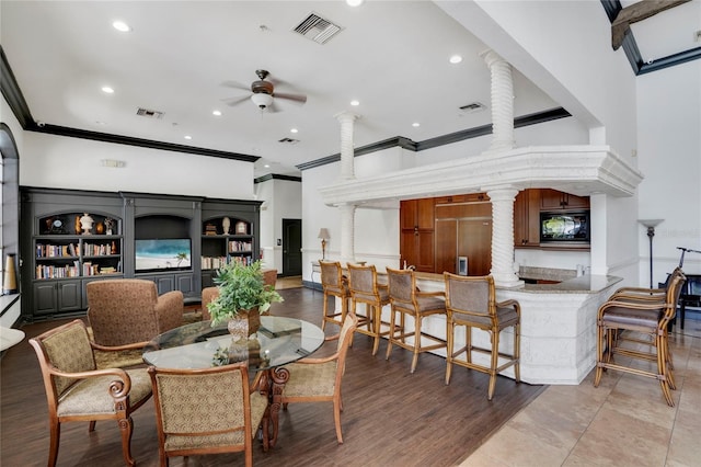 dining space featuring ornate columns, ornamental molding, ceiling fan, and light hardwood / wood-style floors