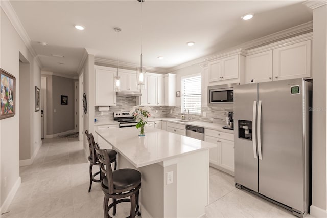 kitchen featuring white cabinets, sink, decorative light fixtures, a kitchen island, and stainless steel appliances