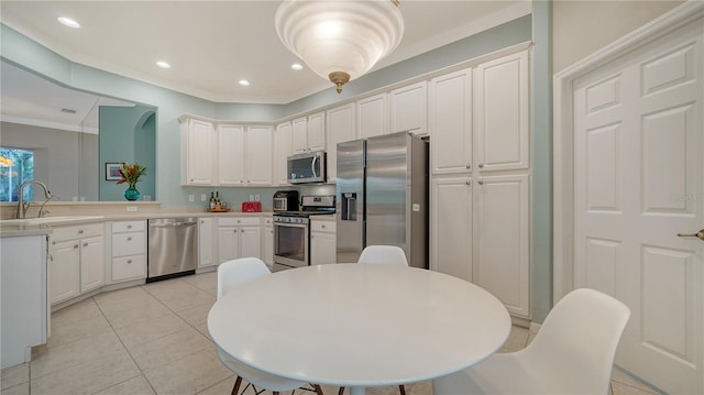 kitchen with kitchen peninsula, appliances with stainless steel finishes, sink, light tile patterned floors, and white cabinetry