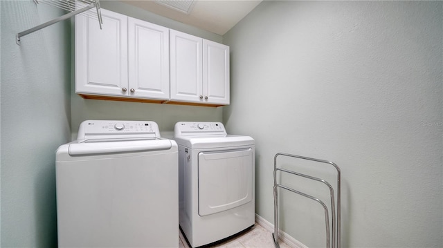 laundry room with washer and dryer, light tile patterned flooring, and cabinets