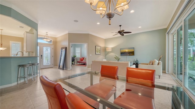 tiled dining space featuring ceiling fan with notable chandelier, ornamental molding, and sink