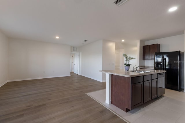 kitchen featuring dark brown cabinetry, sink, black refrigerator with ice dispenser, light wood-type flooring, and a kitchen island with sink