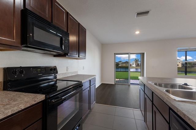 kitchen featuring sink, tile patterned floors, dark brown cabinets, and black appliances