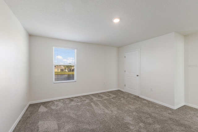 carpeted spare room with a textured ceiling