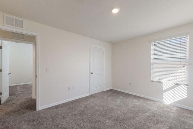 carpeted empty room with a textured ceiling