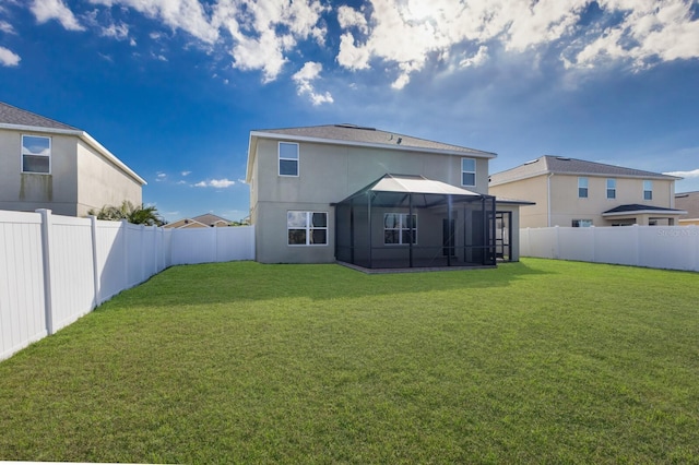 rear view of property with glass enclosure and a lawn