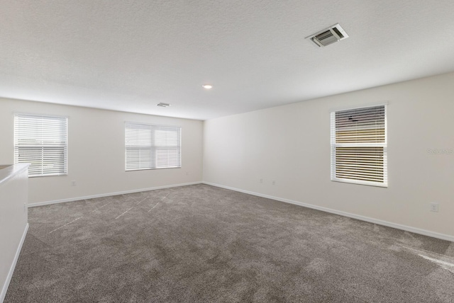 empty room with a textured ceiling and dark colored carpet