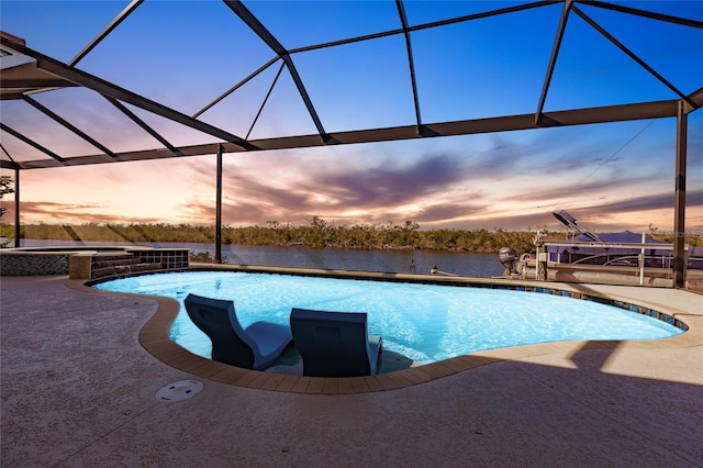 pool at dusk with glass enclosure and a patio area