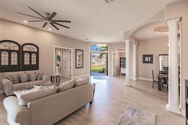 living room with light wood-type flooring, decorative columns, and ceiling fan