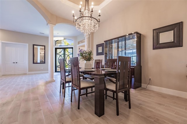 dining room featuring an inviting chandelier, ornate columns, ornamental molding, and light hardwood / wood-style flooring