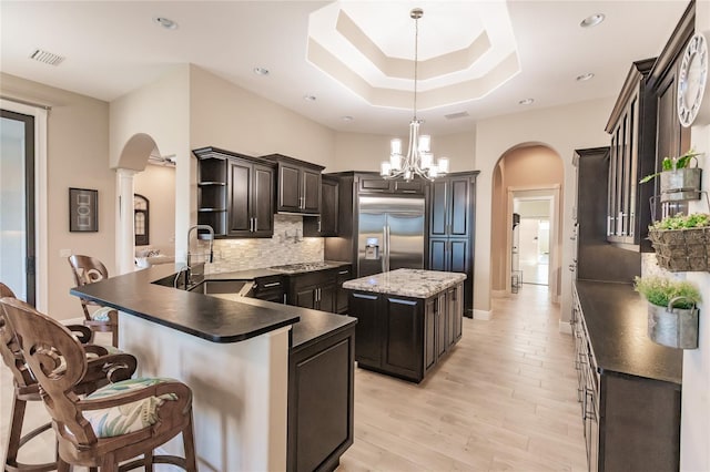 kitchen with sink, a center island, kitchen peninsula, built in refrigerator, and pendant lighting