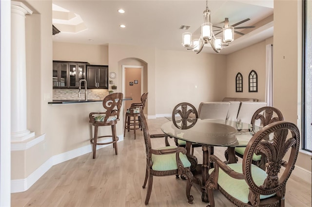 dining room with decorative columns, light hardwood / wood-style flooring, a notable chandelier, and sink