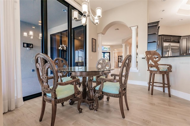 dining area with decorative columns, light hardwood / wood-style flooring, and a notable chandelier