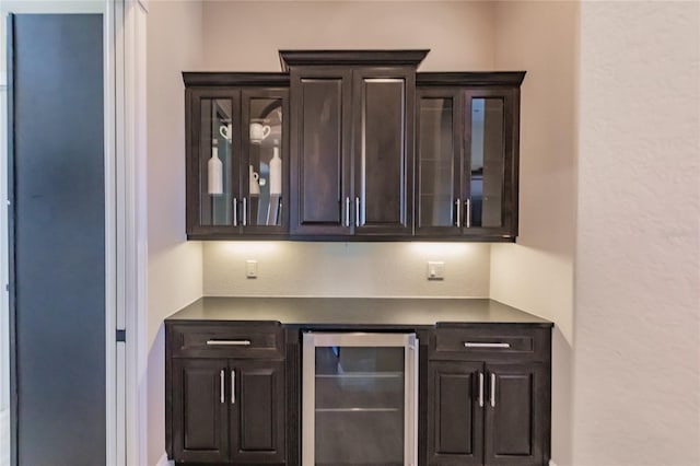 bar with dark brown cabinetry and beverage cooler