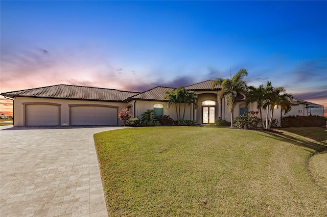 mediterranean / spanish-style home with a lawn and a garage