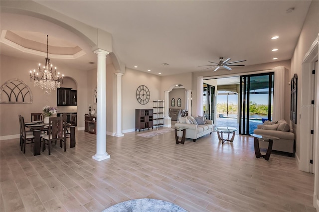 living room featuring ceiling fan with notable chandelier, light hardwood / wood-style flooring, and decorative columns