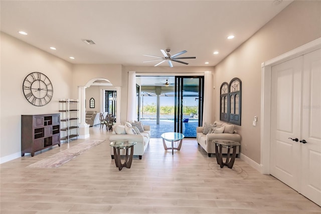 living room with light hardwood / wood-style floors, ornate columns, and ceiling fan