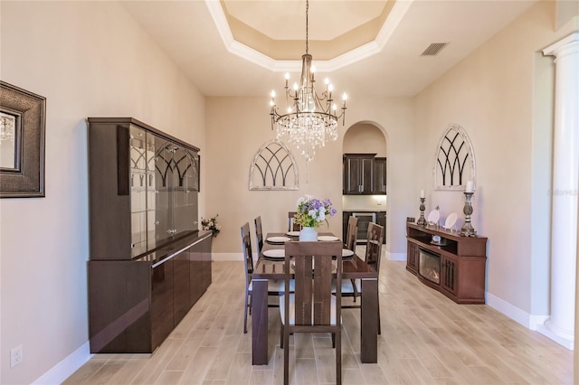 dining room featuring a tray ceiling, light hardwood / wood-style flooring, and a chandelier