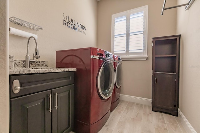 washroom featuring light hardwood / wood-style floors, cabinets, sink, and washing machine and clothes dryer