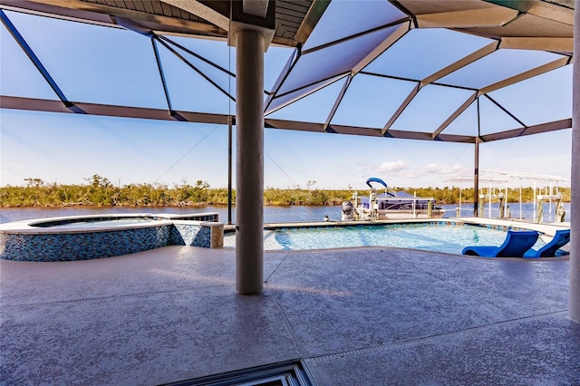 view of swimming pool featuring glass enclosure, an in ground hot tub, a patio area, and a water view