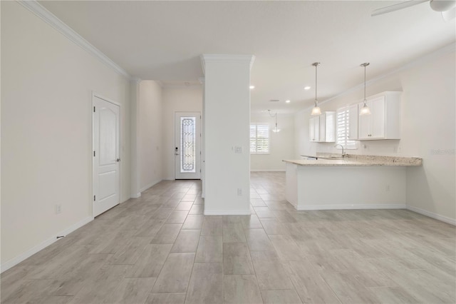 kitchen featuring kitchen peninsula, light stone countertops, white cabinets, and ornamental molding