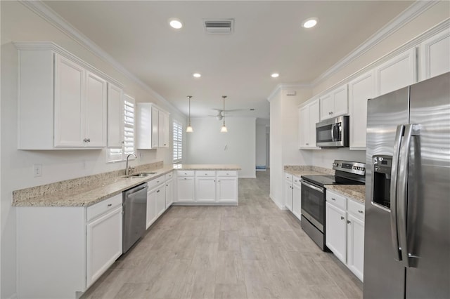 kitchen with light stone counters, kitchen peninsula, pendant lighting, white cabinets, and appliances with stainless steel finishes