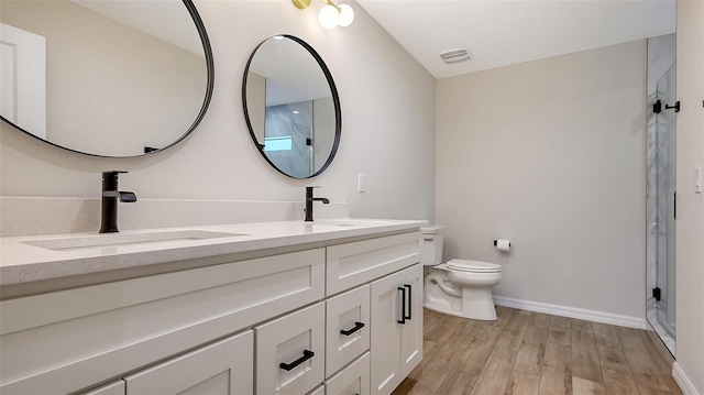 bathroom with hardwood / wood-style floors, vanity, a shower with door, and toilet