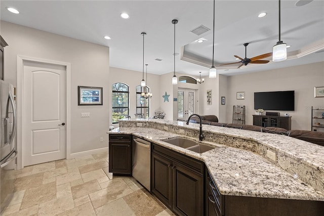 kitchen featuring sink, ceiling fan, appliances with stainless steel finishes, a tray ceiling, and decorative light fixtures