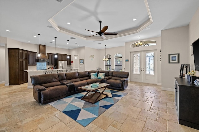 living room featuring french doors, ceiling fan with notable chandelier, and a tray ceiling