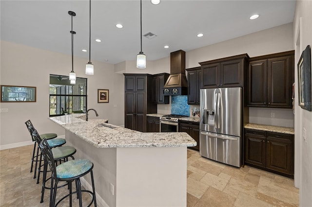 kitchen with stainless steel appliances, sink, wall chimney range hood, pendant lighting, and a large island