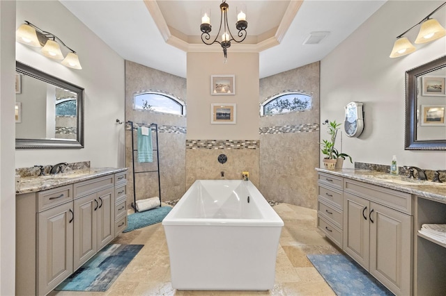 bathroom with a washtub, a chandelier, a tray ceiling, vanity, and tile walls