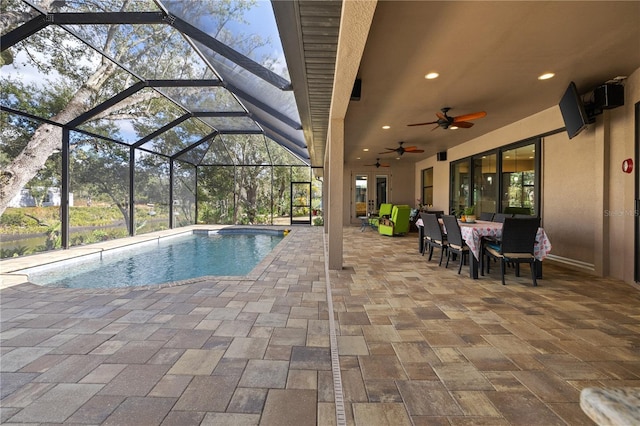 view of pool with glass enclosure, a patio area, and ceiling fan