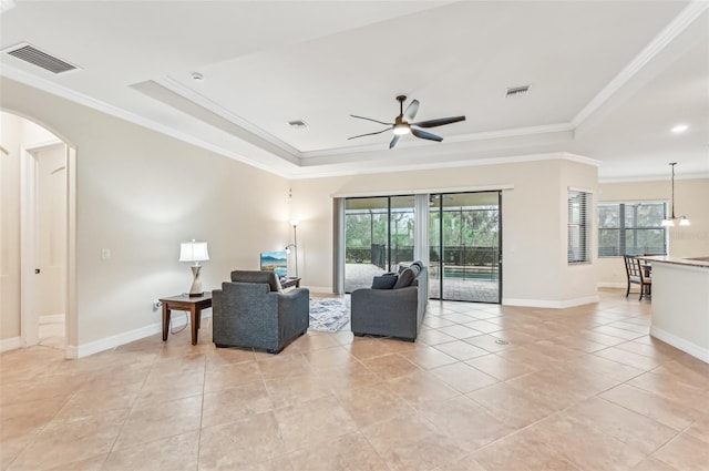 living room with a tray ceiling, ceiling fan, and ornamental molding