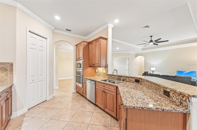 kitchen featuring light stone countertops, ceiling fan, sink, stainless steel appliances, and ornamental molding