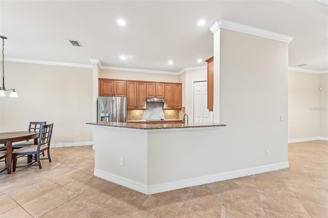 kitchen featuring hanging light fixtures, decorative backsplash, dark stone countertops, ornamental molding, and stainless steel fridge with ice dispenser