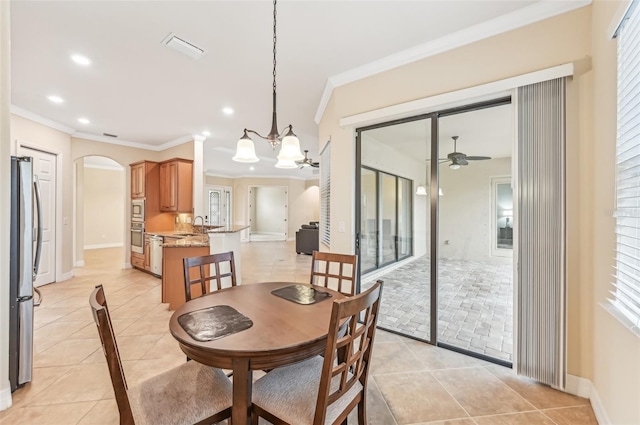 dining room featuring ceiling fan with notable chandelier, a healthy amount of sunlight, light tile patterned floors, and crown molding