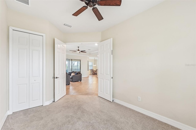 unfurnished bedroom with light carpet, a closet, and ceiling fan