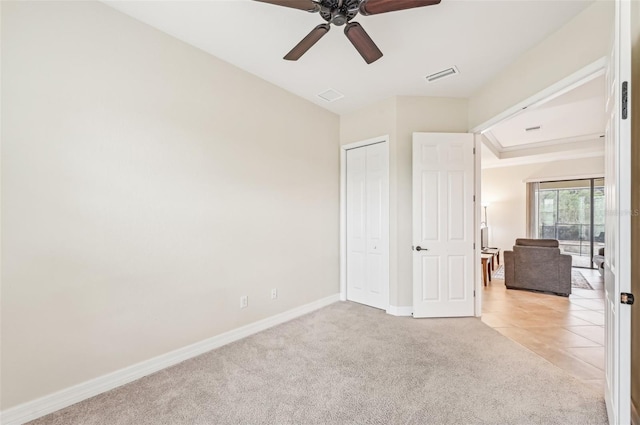 unfurnished bedroom with light carpet, a closet, and ceiling fan