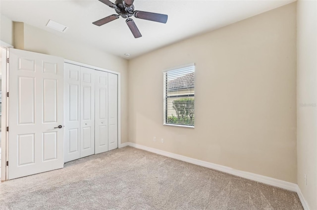 unfurnished bedroom with a closet, light colored carpet, and ceiling fan