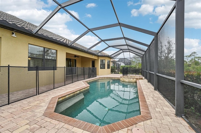 view of pool featuring an in ground hot tub, a patio, glass enclosure, and ceiling fan