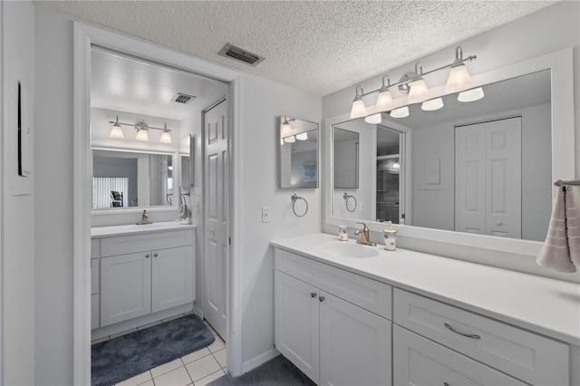 bathroom with tile patterned floors, vanity, and a textured ceiling