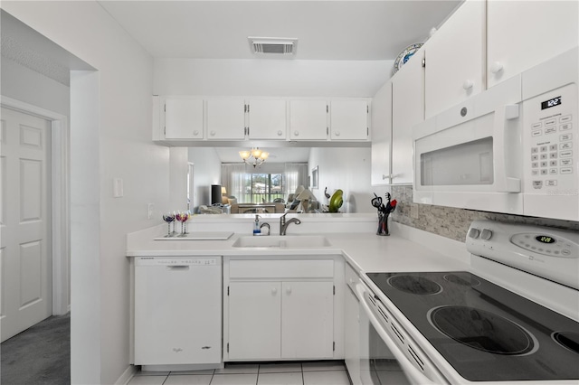 kitchen with white appliances, sink, light tile patterned floors, a notable chandelier, and white cabinets