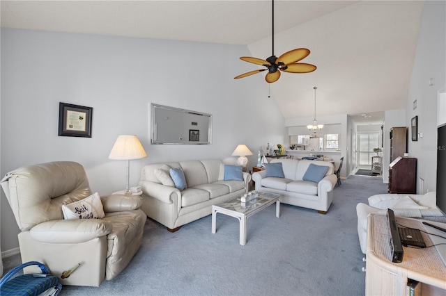 carpeted living room with ceiling fan with notable chandelier and high vaulted ceiling