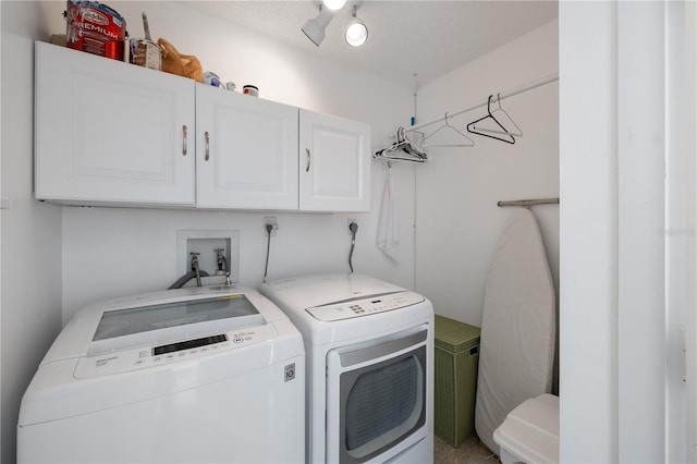 laundry area featuring washing machine and clothes dryer and cabinets