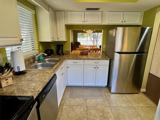 kitchen featuring appliances with stainless steel finishes, light tile patterned floors, white cabinetry, and sink